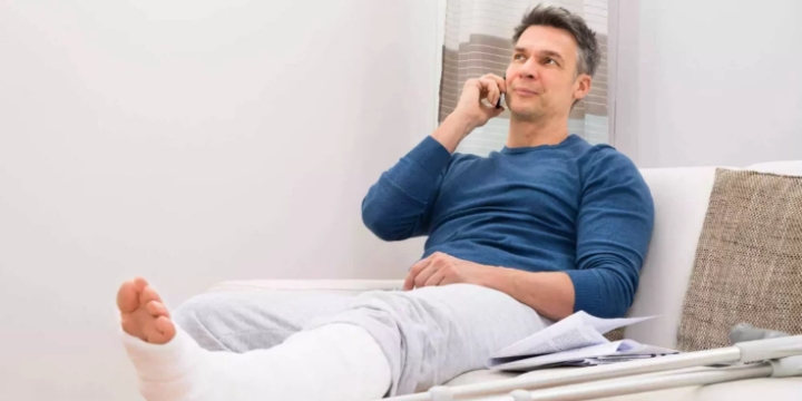 Mandant mit Gipsbein telefoniert entspannt auf dem Sofa, Symbolbild für einen erfolgreichen Fall