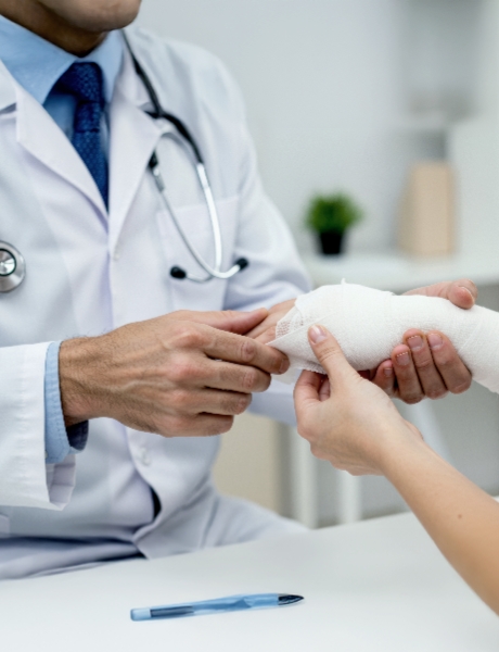 Arzt untersucht das bandagierte Handgelenk eines Patienten in der Praxis