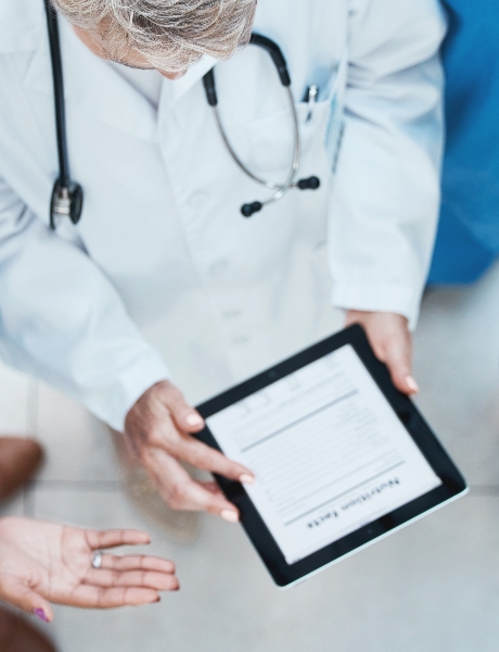 Ärzteteam bespricht sich mit einem Tablet im Rahmen einer medizinischen Beratung