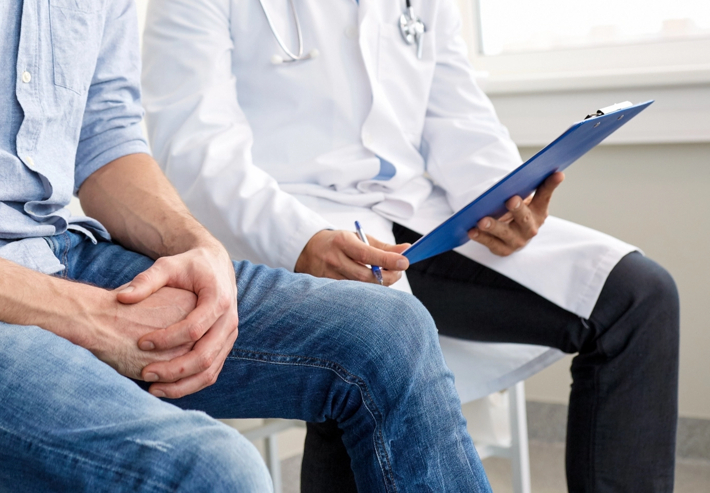 Arzt bespricht mit Klemmbrett den Gesundheitszustand eines jungen Patienten in der Klinik, Symbolbild Urologiefehler