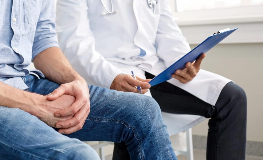 Arzt bespricht mit Klemmbrett den Gesundheitszustand eines jungen Patienten in der Klinik, Symbolbild Urologiefehler