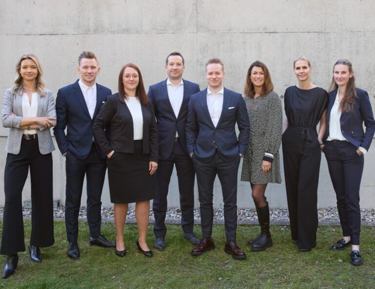 Gruppenfoto des Teams der Kanzlei Friese & Adelung vor einer Betonwand im Freien